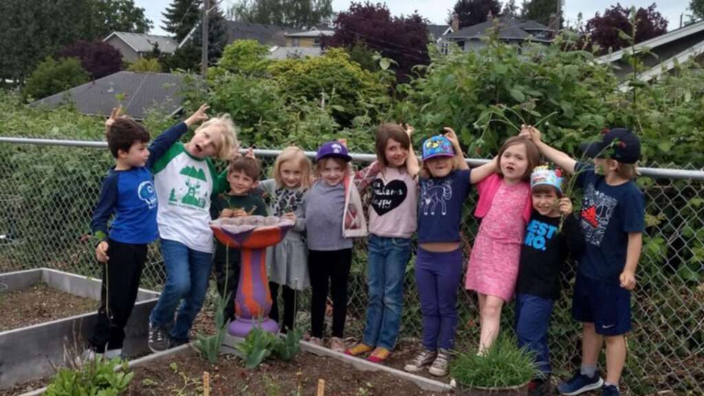 Boys and Girls are standing besides a garden