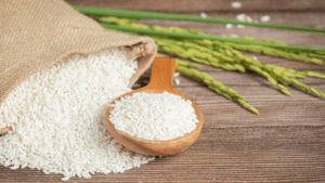 Sack of rice with rice on wooden spoon and rice plant