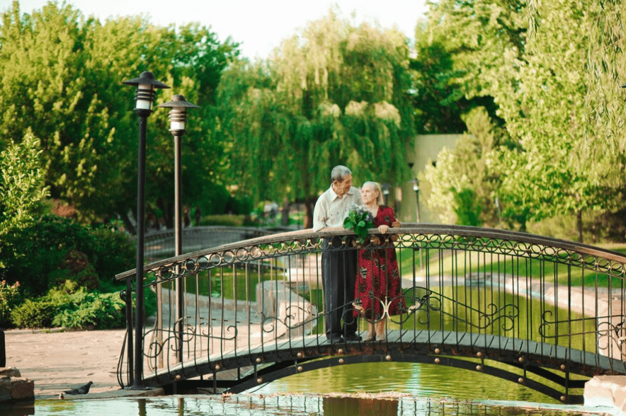 Happy senior couple standing on the bridge near river