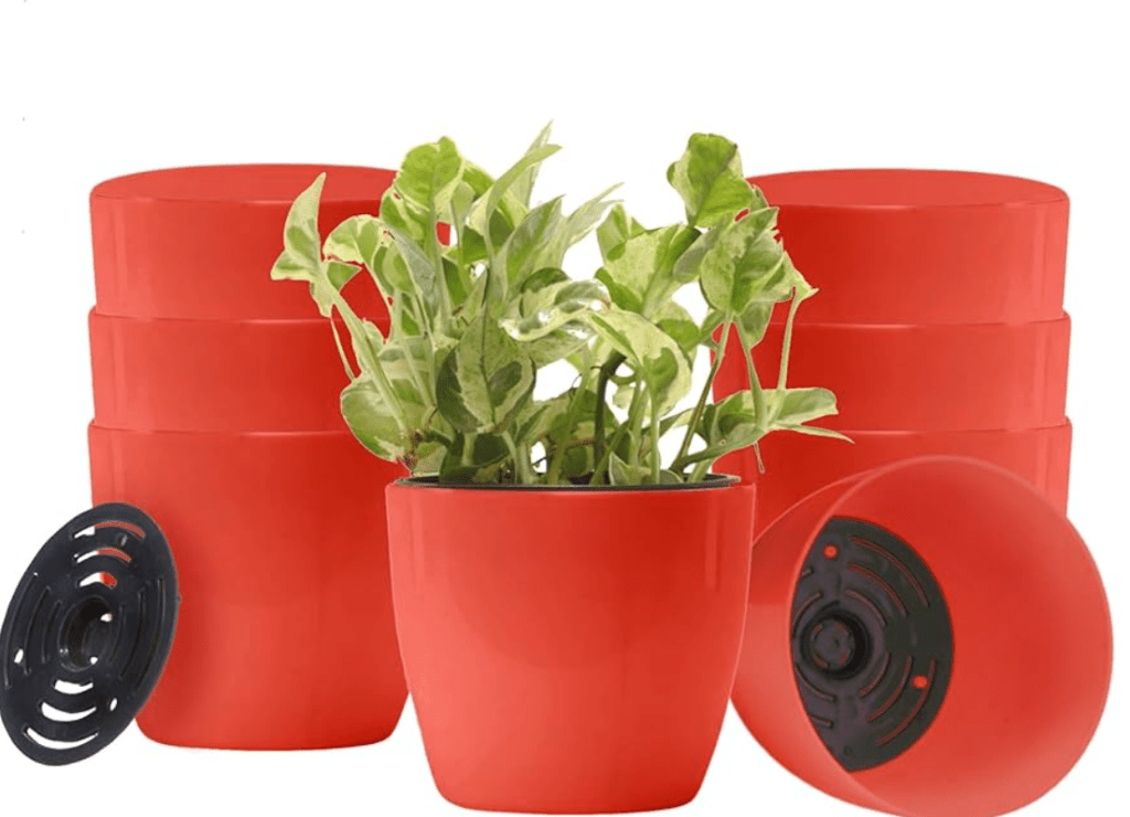 A green plant in a red pot with self-watering system, alongside four stacked identical pots.