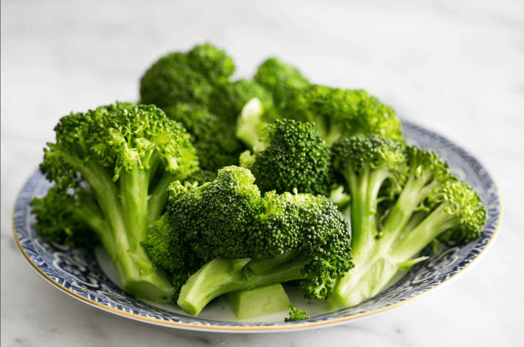 Fresh broccoli florets on a patterned blue and white plate.