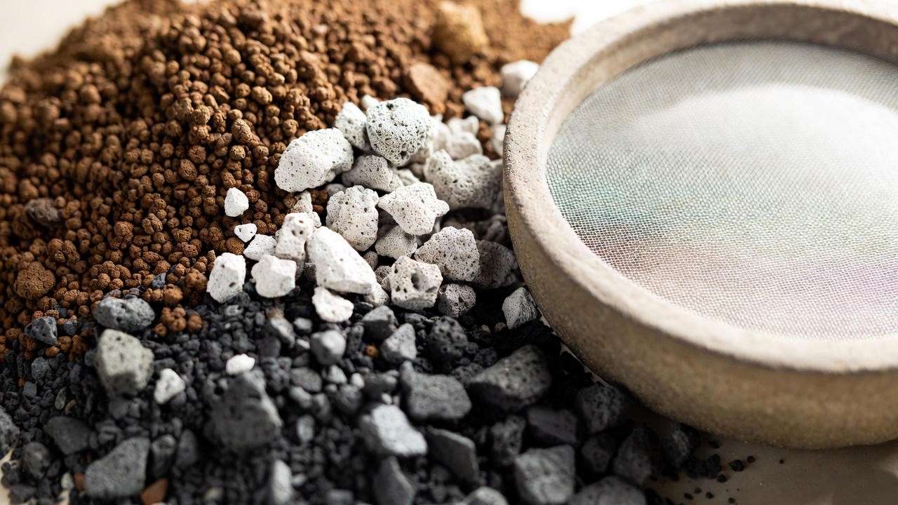  “Akadama, pumice, and lava rock soil mix displayed with an unglazed bonsai pot for proper drainage.” 