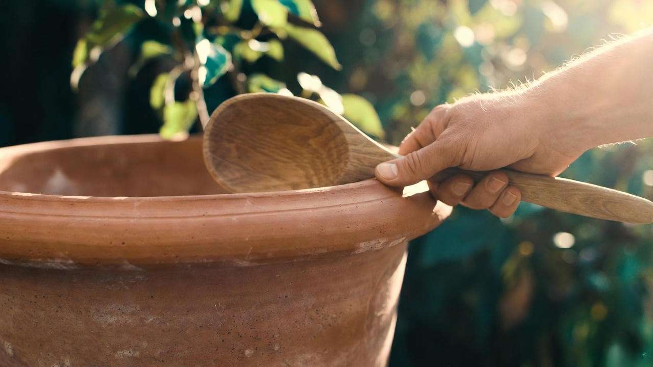 Hand performing the ring test on a high-fired large terracotta plant pot to check quality