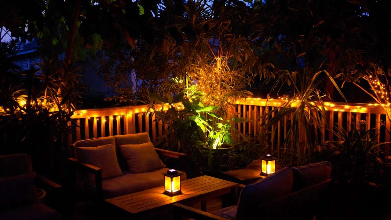 cozy small garden seating area with fairy lights and solar lanterns at night