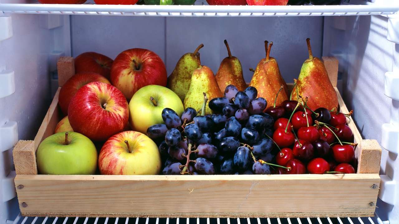 resh apples, pears, grapes, and cherries in wooden crate ready for cold storage in refrigerator
