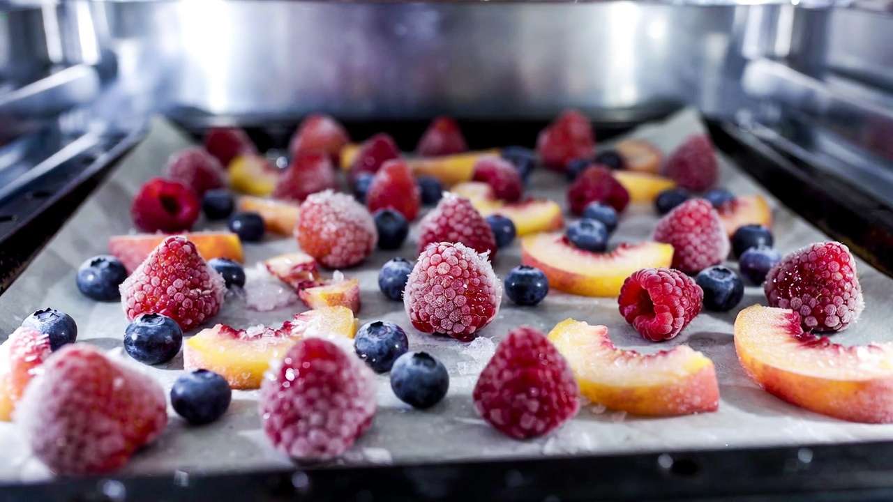 Flash-frozen homegrown berries and peach slices on trays for easy long-term freezer storage