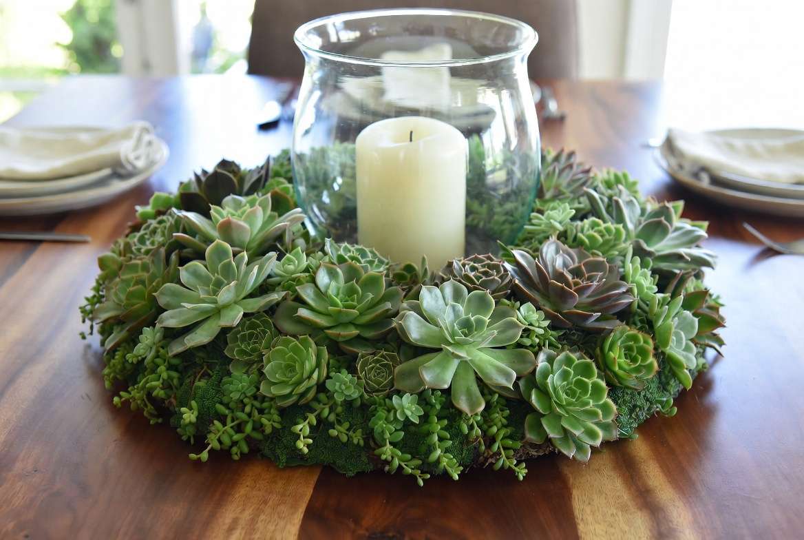 A thriving, fully established living succulent wreath displayed horizontally as a beautiful centerpiece with a candle, showing inspirational succulent wreath decor for the home.