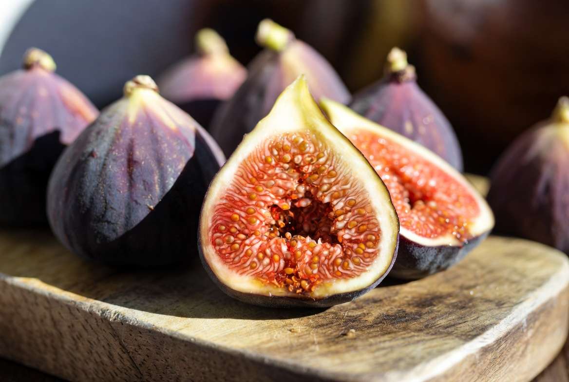 Freshly harvested ripe Mission fig cut open on a rustic wooden board