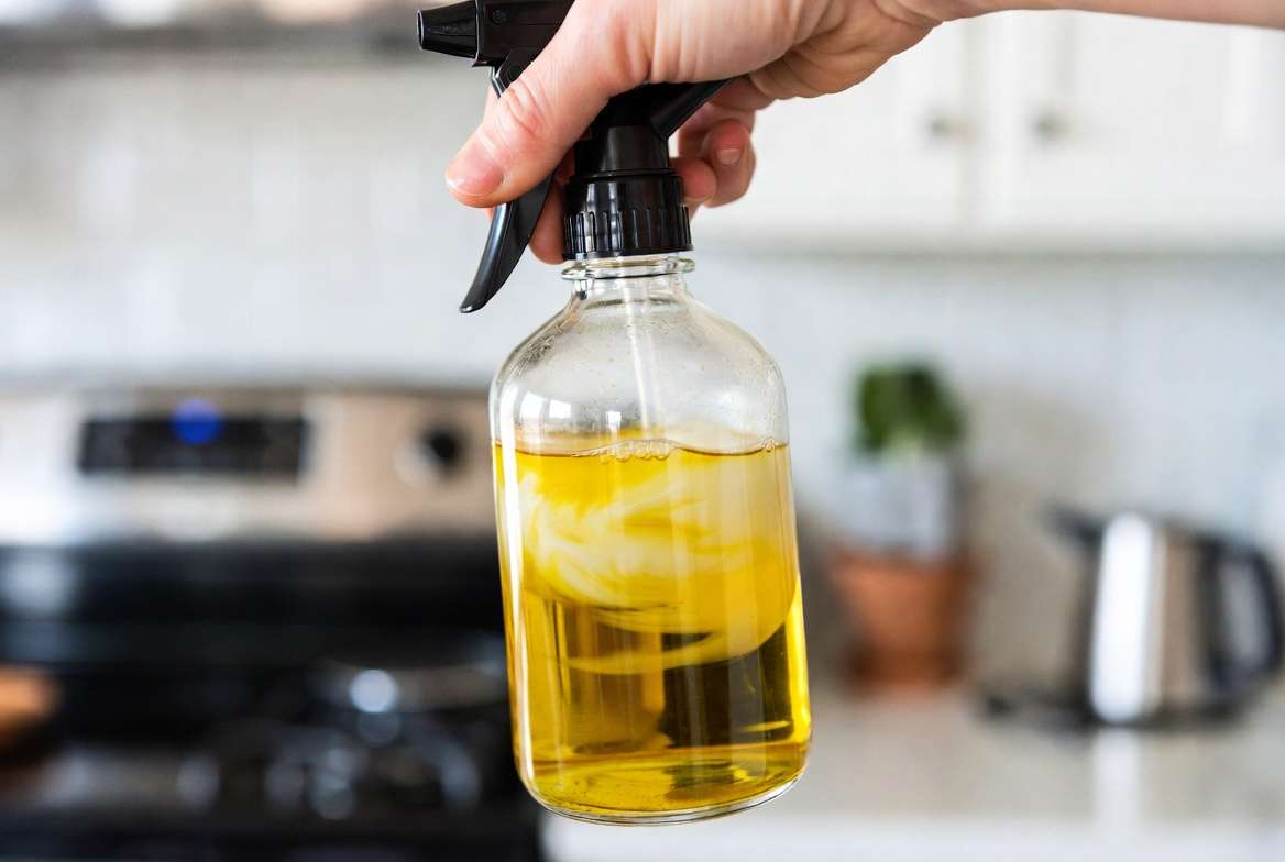 Close-up shot of a gardener swirling a glass bottle, showing neem oil emulsifying and turning water milky yellow with castile soap.
